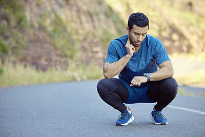 Buy stock photo Full length shot of a handsome young man crouching and timing his pulse during his outdoor workout