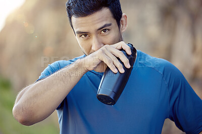 Buy stock photo Shot of a handsome young man standing alone and taking a break during his outdoor workout