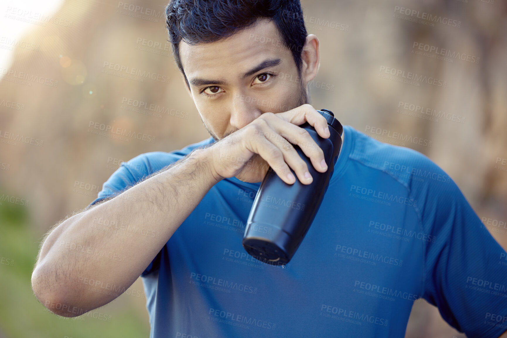 Buy stock photo Shot of a handsome young man standing alone and taking a break during his outdoor workout