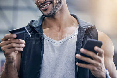 Buy stock photo Closeup shot of a muscular young man using a cellphone and credit card in a gym