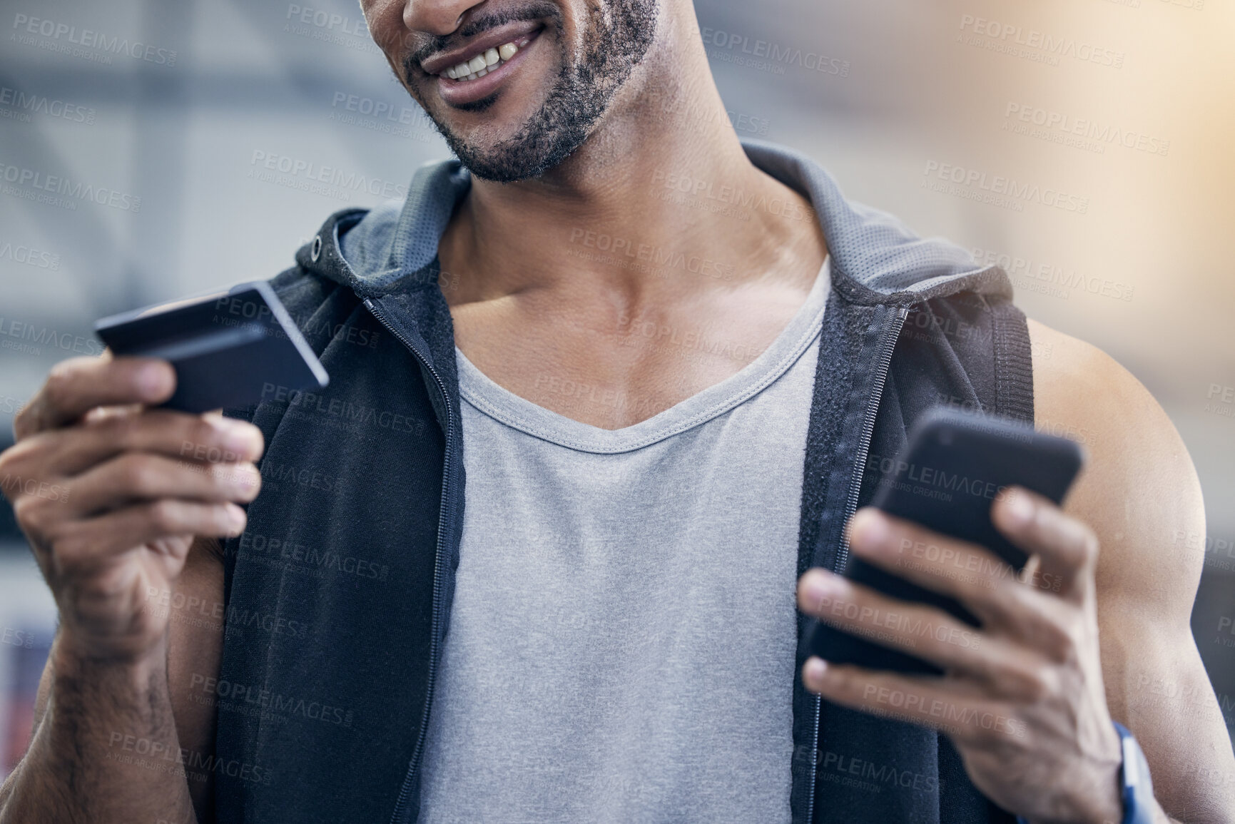 Buy stock photo Closeup shot of a muscular young man using a cellphone and credit card in a gym