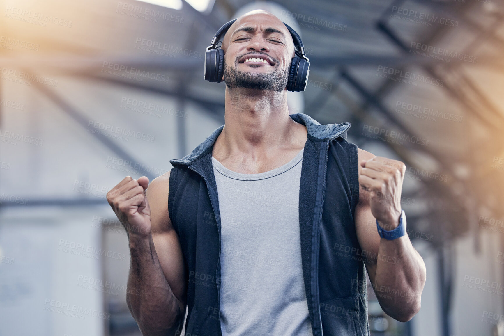 Buy stock photo Shot of a muscular young man cheering while listening to music in a gym