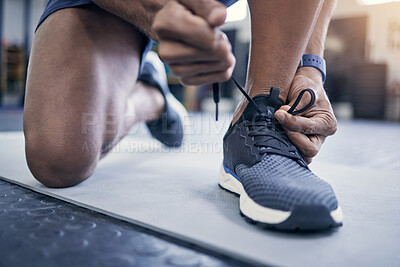 Buy stock photo Closeup shot of an unrecognisable man tying his laces in a gym