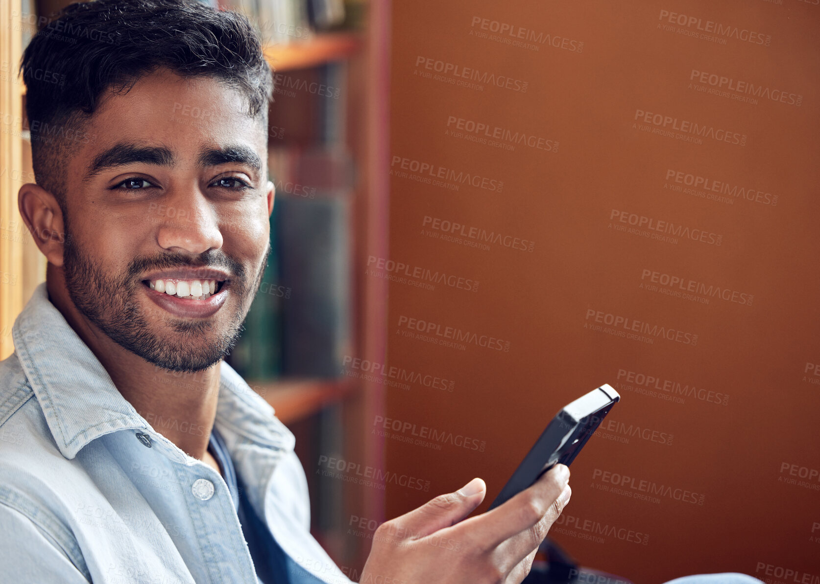 Buy stock photo Male student, portrait and smile with smartphone in library for study in university for higher education. Scholarship, academic and social media or person for knowledge on campus with happiness.