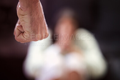 Buy stock photo Shot of a man’s fist with a woman looking scared in the background