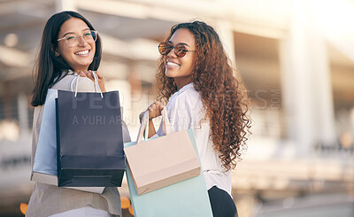 Buy stock photo Portrait of two attractive young women standing outside together and bonding while shopping in the city
