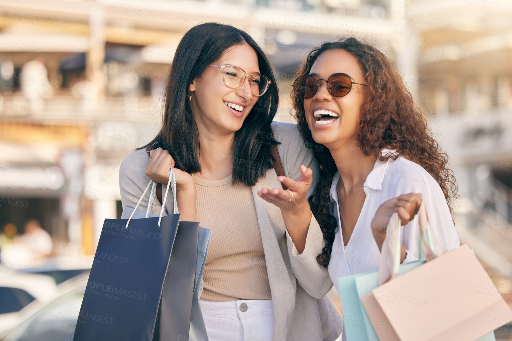 Buy stock photo Shot of two attractive young women standing outside together and bonding while shopping in the city