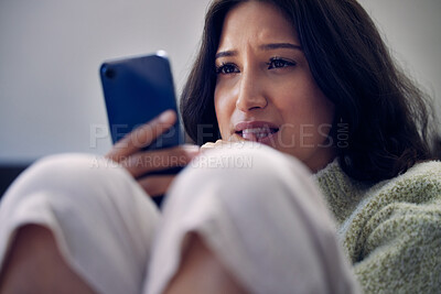 Buy stock photo Shot of a young woman using a smartphone and looking unhappy at home