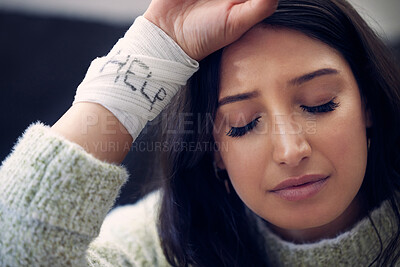 Buy stock photo Shot of a young woman with bandages wrapped around her wrists showing “help” written on them