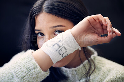 Buy stock photo Shot of a young woman with bandages wrapped around her wrists showing “help” written on them