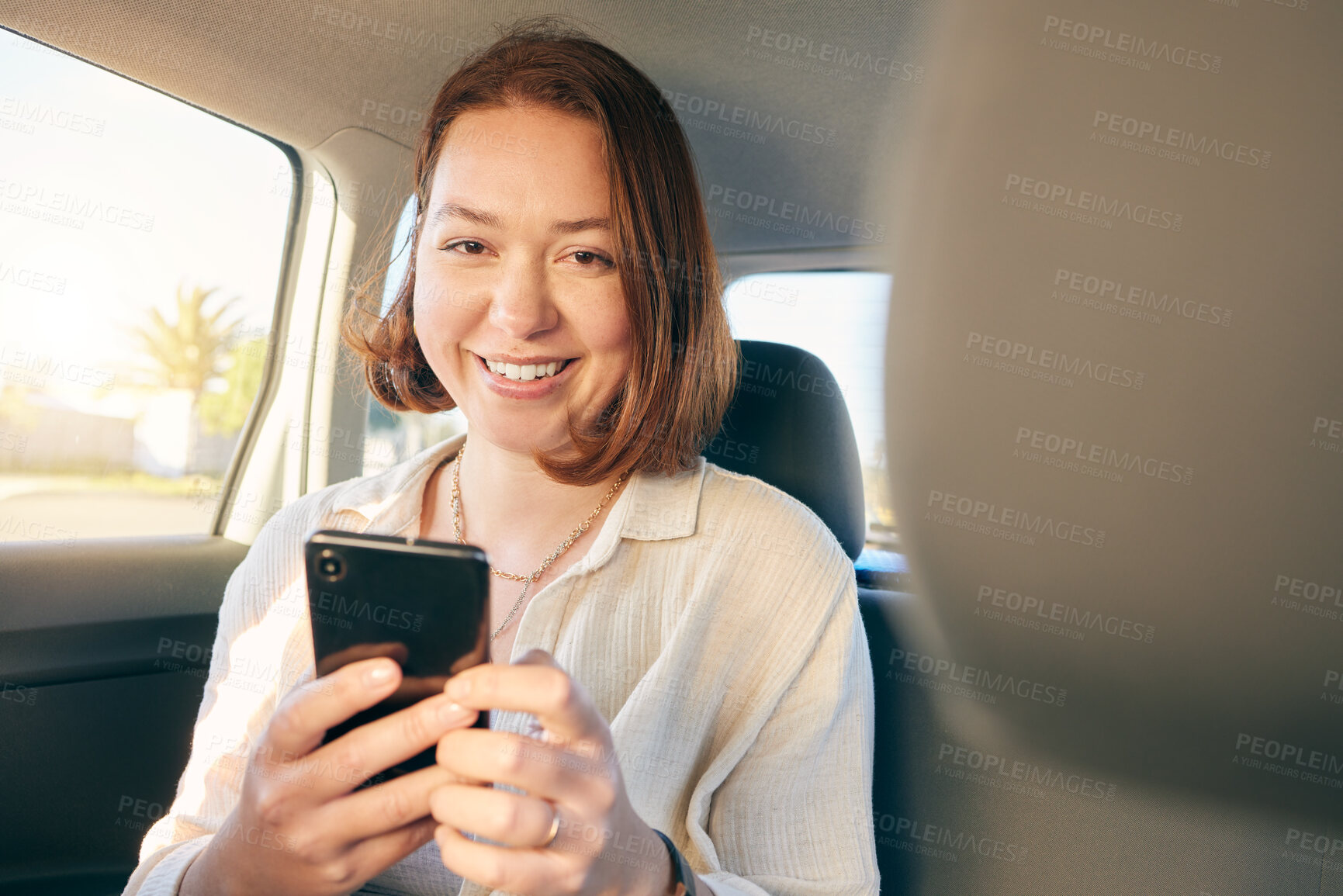 Buy stock photo Shot of a young woman using a smartphone while traveling in a car