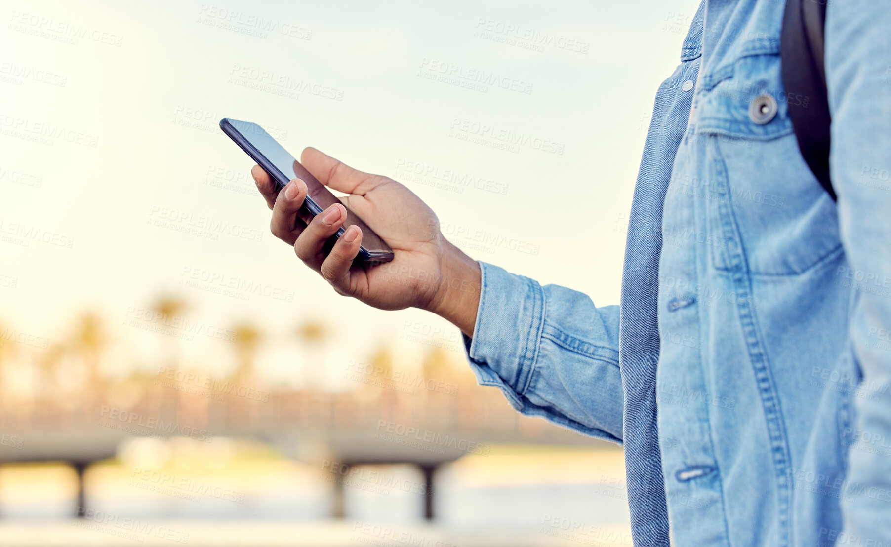 Buy stock photo Cropped shot of a man using his cellphone while standing outside