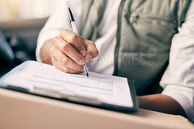 Buy stock photo Shot of a delivery man writing on a clipboard while sitting in his vehicle