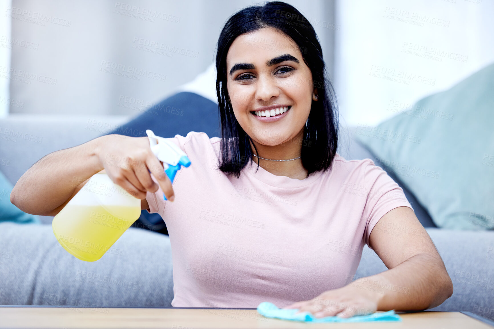 Buy stock photo Shot of a young woman cleaning a table at home