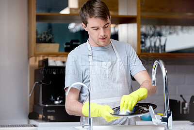 Buy stock photo Shot of a young man washing dishes in his kitchen