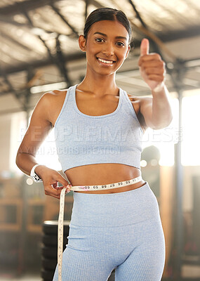 Buy stock photo Portrait of a fit young woman measuring her waistline in a gym