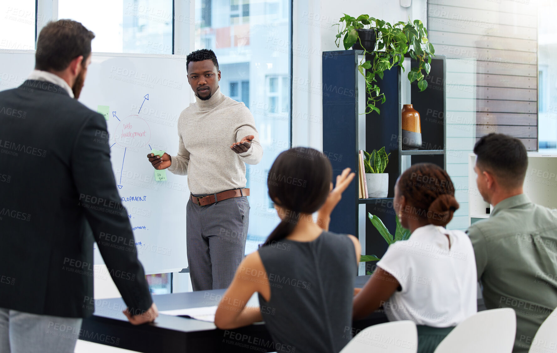 Buy stock photo Shot of a young businessman leading a presentation to his colleagues in an office