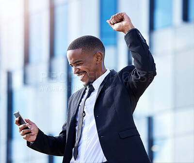 Buy stock photo Shot of a young businessman cheering while using a phone in the city