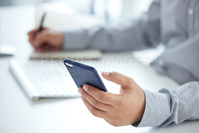 Buy stock photo Closeup shot of an unrecognisable businessman using a cellphone while writing notes in an office