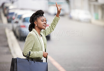 Buy stock photo Shot of a young woman hailing a cab after a day of shopping
