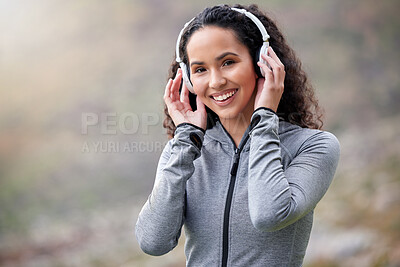 Buy stock photo Shot of a fit young woman wearing headphones while out in the mountains