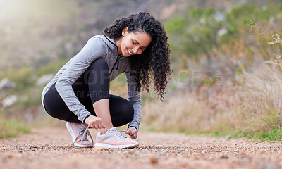 Buy stock photo Shot of a woman tying her shoelaces while out on a trail for a run