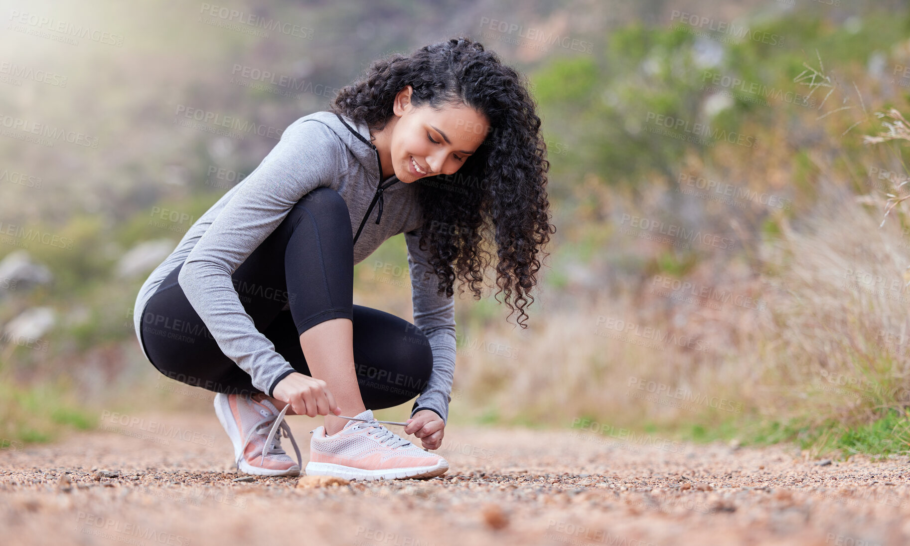 Buy stock photo Shot of a woman tying her shoelaces while out on a trail for a run