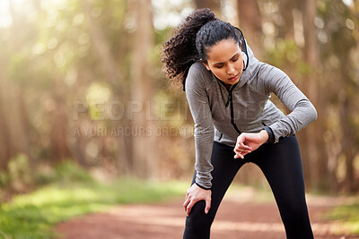 Buy stock photo Woman, tired and checking watch in nature for distance, fitness and wellness in forest. Brazilian runner, taking break and counting steps from workout, challenge and goals in woods with copy space