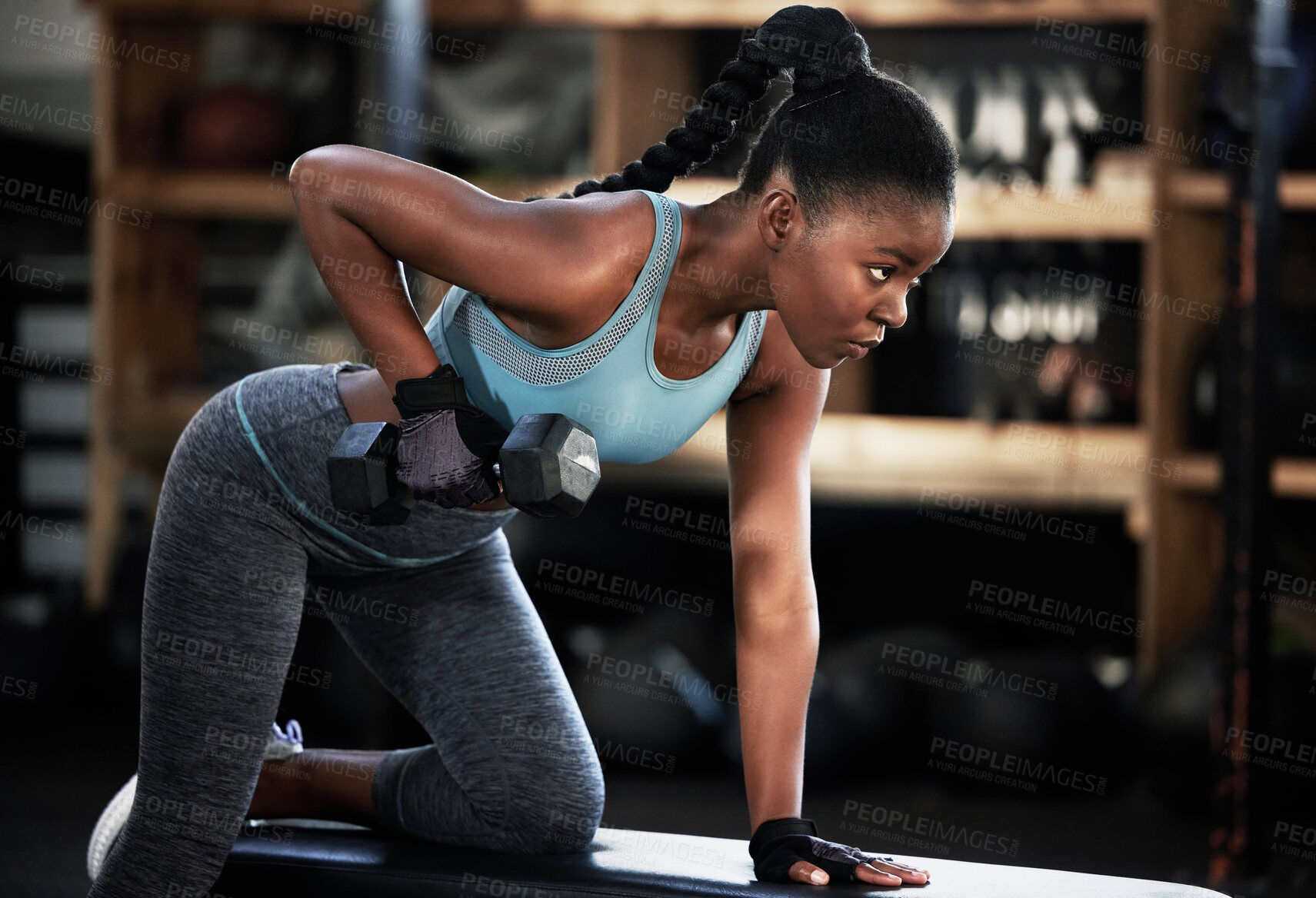 Buy stock photo Shot of a fit young woman working out with a dumbbell at the gym
