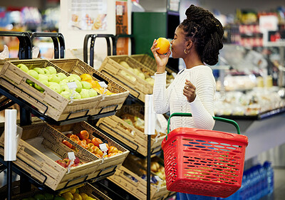 Buy stock photo Shot of a young woman browsing through the produce section of a grocery store
