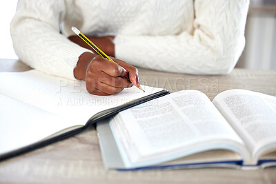 Buy stock photo Shot of an unrecognisable woman making notes in a book while studying at home