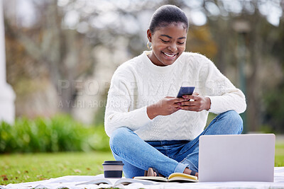 Buy stock photo Shot of a young woman using a smartphone and laptop on the grass at college