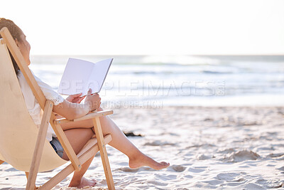 Buy stock photo Shot of an unrecognizable woman reading a book at the beach