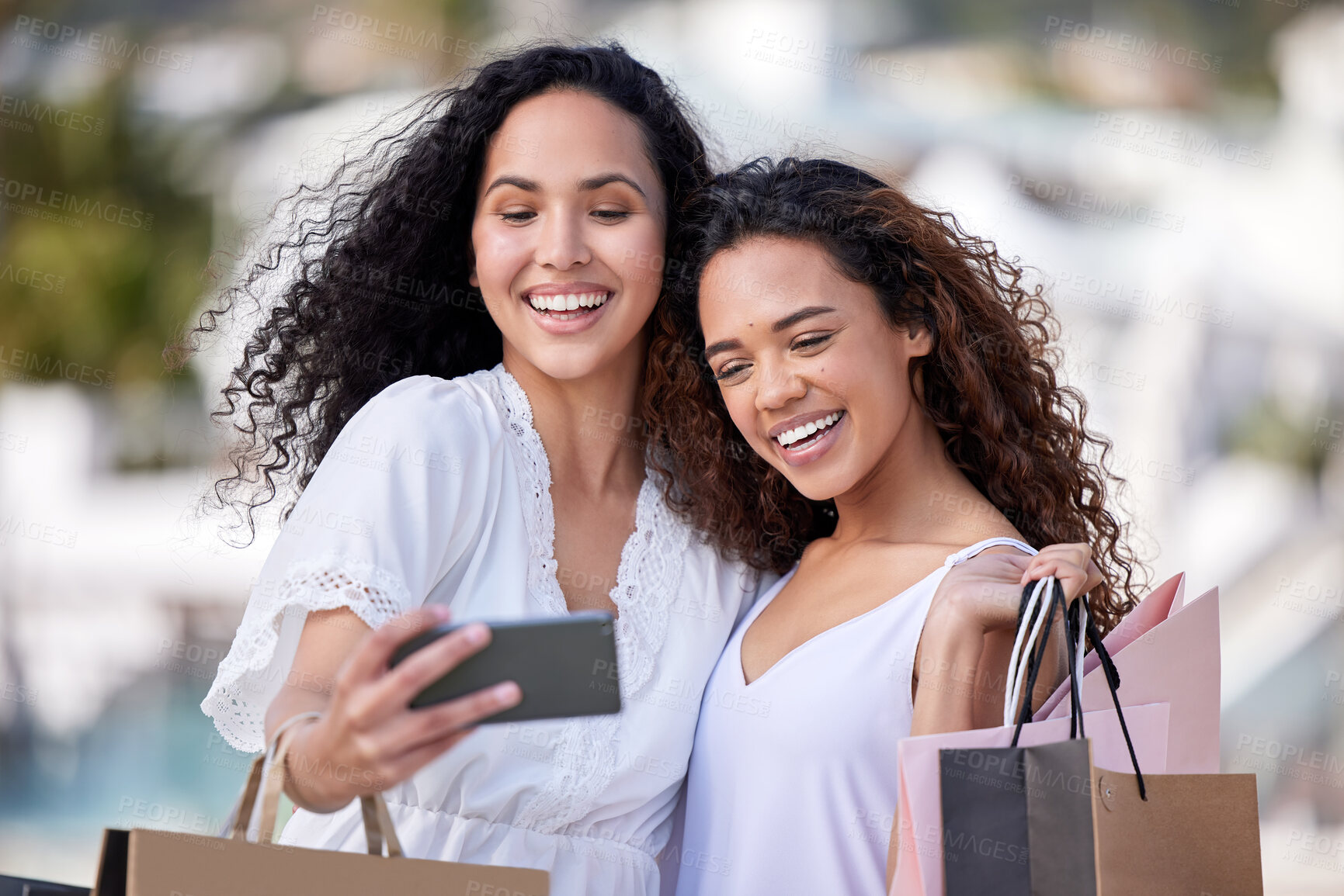 Buy stock photo Shot of two young women taking selfies while shopping against an urban background