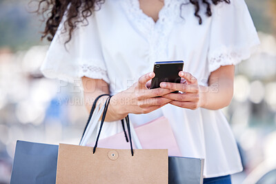 Buy stock photo Shot of a woman using a smartphone while shopping against an urban background