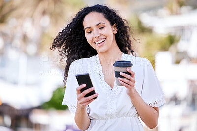 Buy stock photo Shot of a young woman using a smartphone and having coffee while taking a walk outside on a sunny day