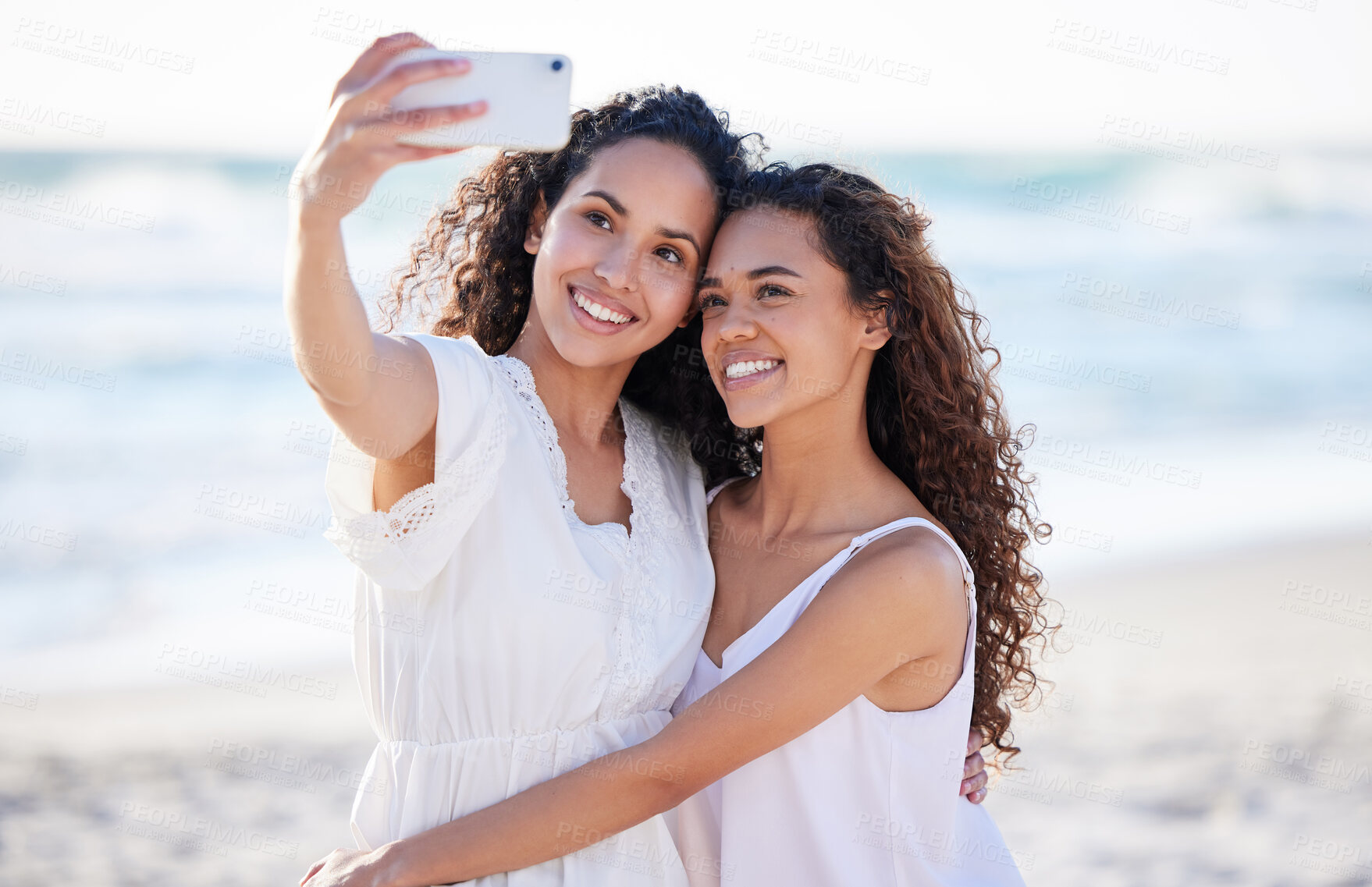 Buy stock photo Shot of two young women taking selfies at the beach