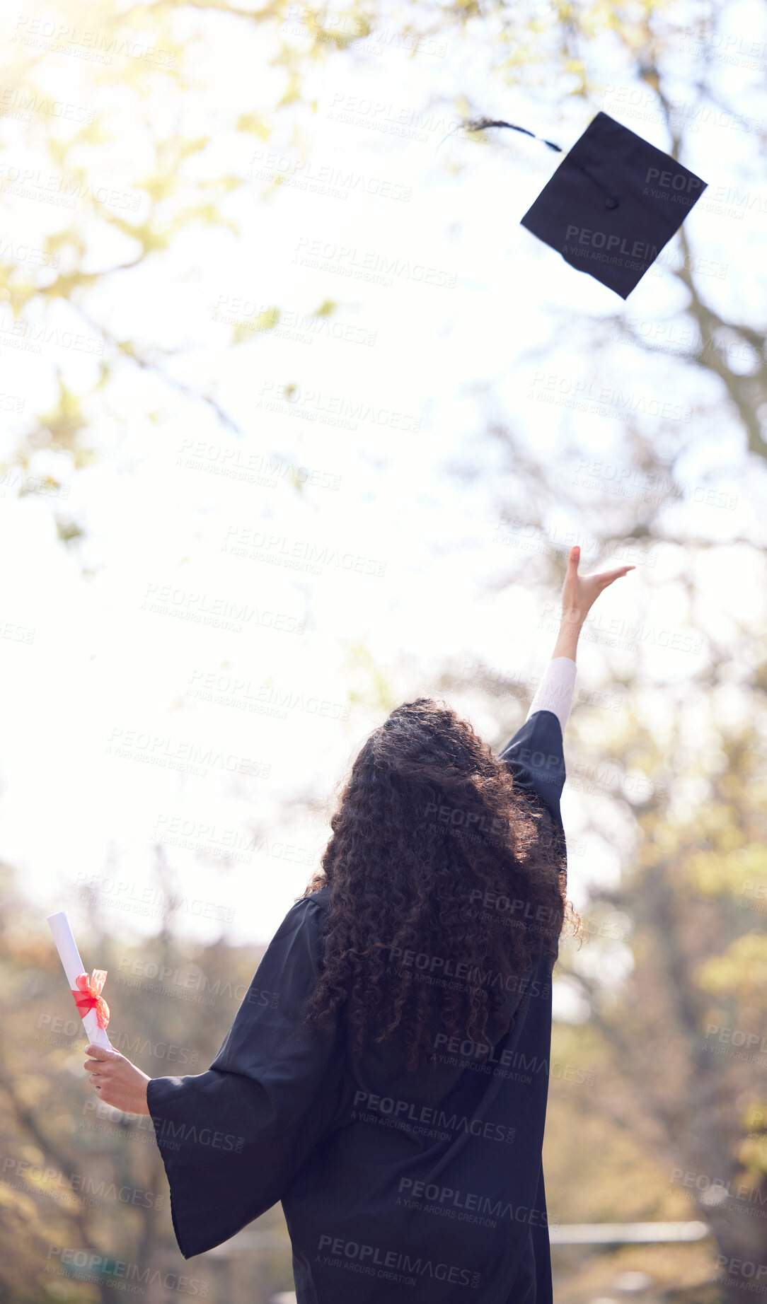 Buy stock photo Rearview shot of a young woman throwing her cap in the air on graduation day
