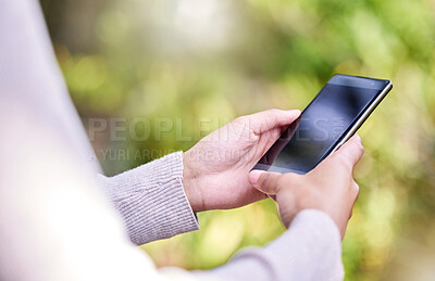 Buy stock photo Shot of an unrecognisable woman using a smartphone out in nature