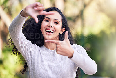 Buy stock photo Shot of a young woman making a finger frame gesture while enjoying a day out in nature