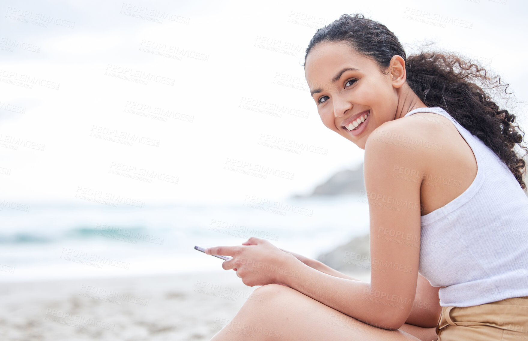 Buy stock photo Woman, portrait and smile on beach with phone for social media scroll, internet browsing or audiobook for relax. Person, happy and smartphone on sand by seaside for holiday, summer vacation or mockup