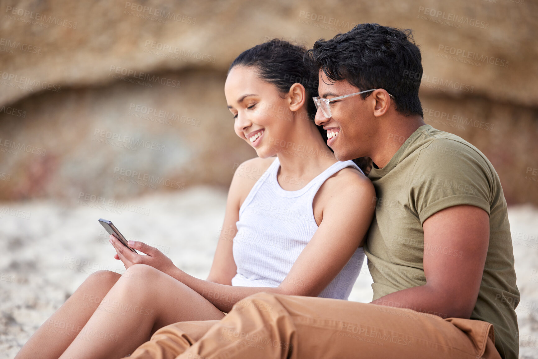 Buy stock photo Beach, couple and vacation together with smartphone, typing and social media or online browse on mobile. Getaway, blog and summer holiday post and outside, smile and happy for love or relax on sand