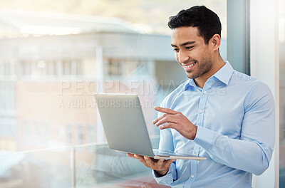 Buy stock photo Shot of a young businessman using his laptop in his office