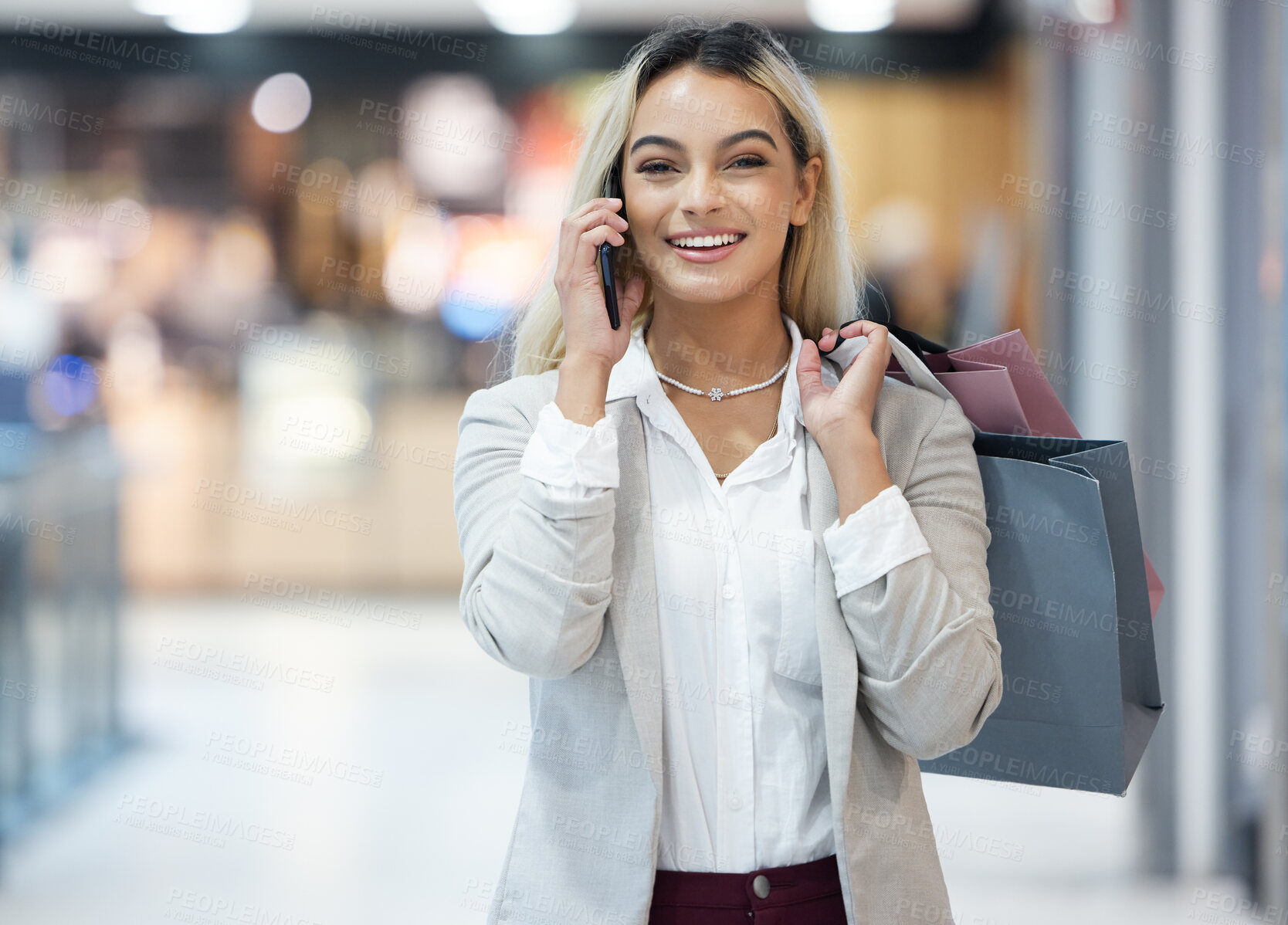 Buy stock photo Shot of a young woman using her smartphone to make a call while shopping