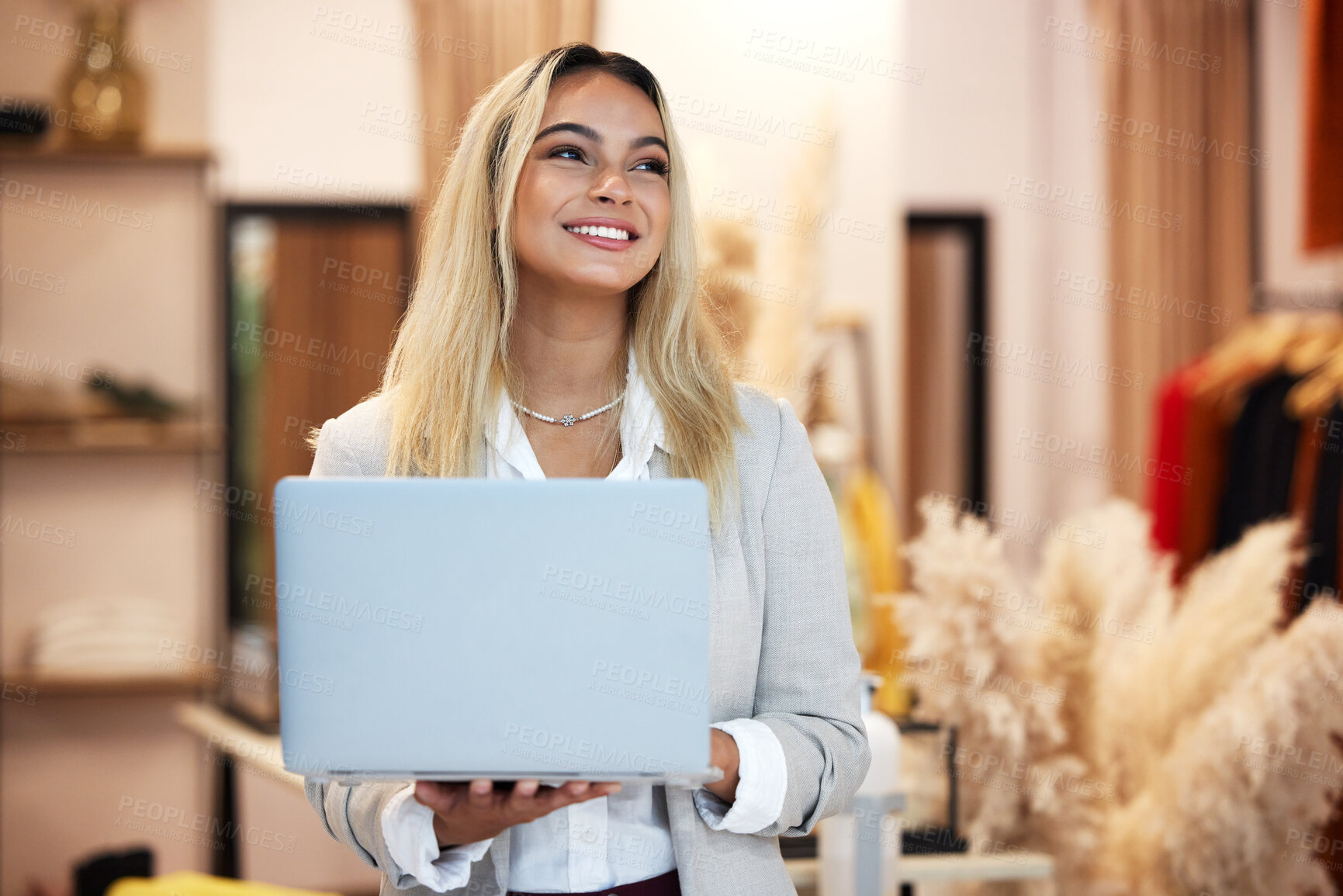 Buy stock photo Shot of a young business owner using a laptop in her clothing store