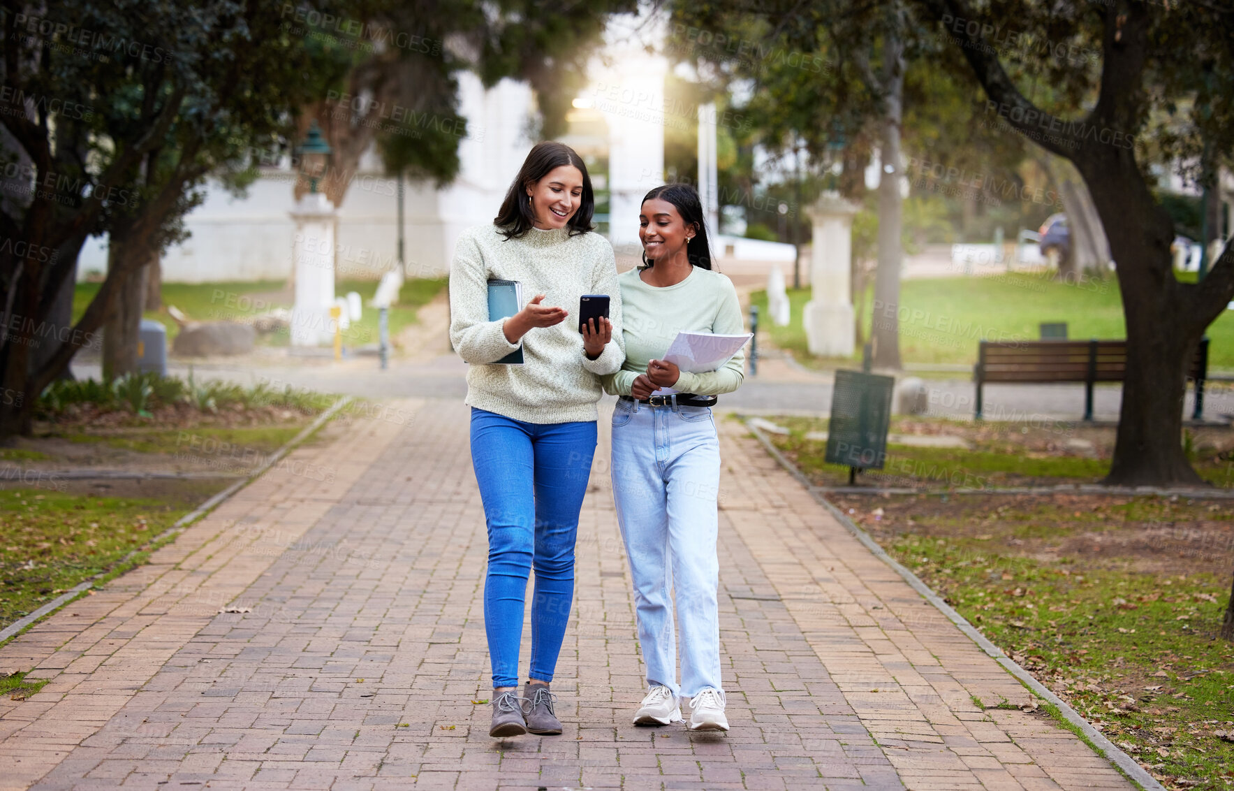 Buy stock photo Happy, female students and friends with a smartphone walking together at university reading exam test results on a mobile app. Technology, smile and college girls on social media or chat on campus