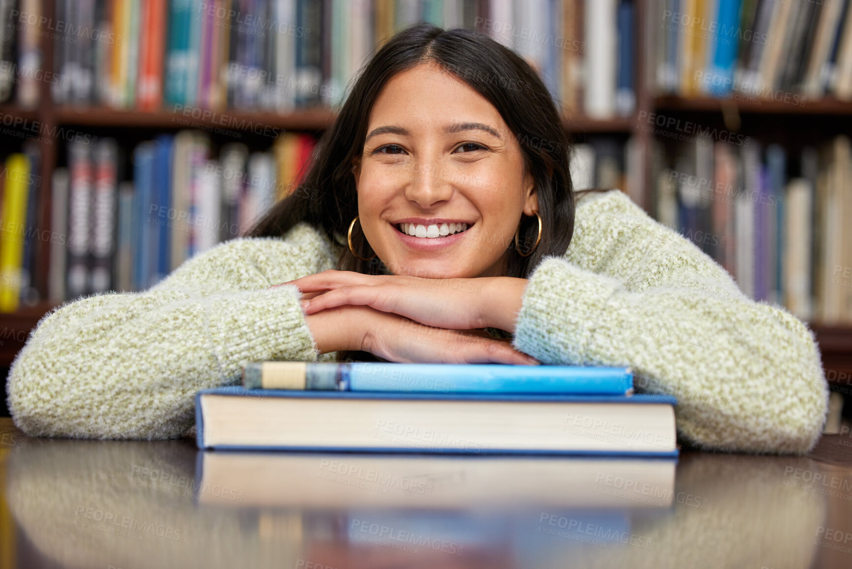 Buy stock photo Shot of a young woman resting on a pile of books in a college library