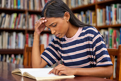 Buy stock photo Shot of a young female student reading a book in a library