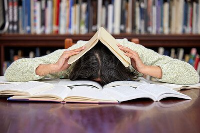 Buy stock photo Shot of a young female studying in a college library and looking stressed