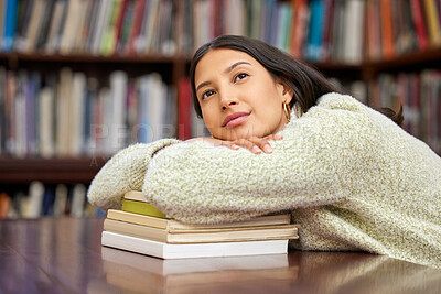 Buy stock photo Shot of a young woman resting on a pile of books in a college library